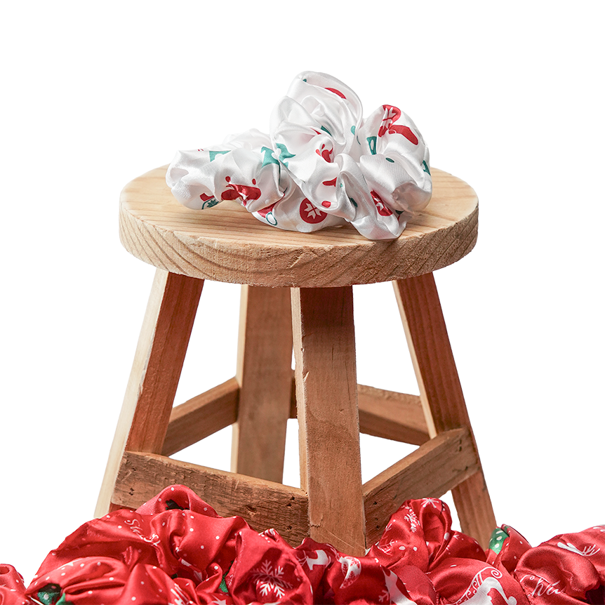 A printed scrunchie on a wooden stool above a pile of red scrunchies
